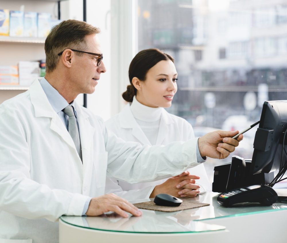 pharmacist-pointing-showing-male-colleague-medication-prices-prescriptions-on-computer-screen.jpg